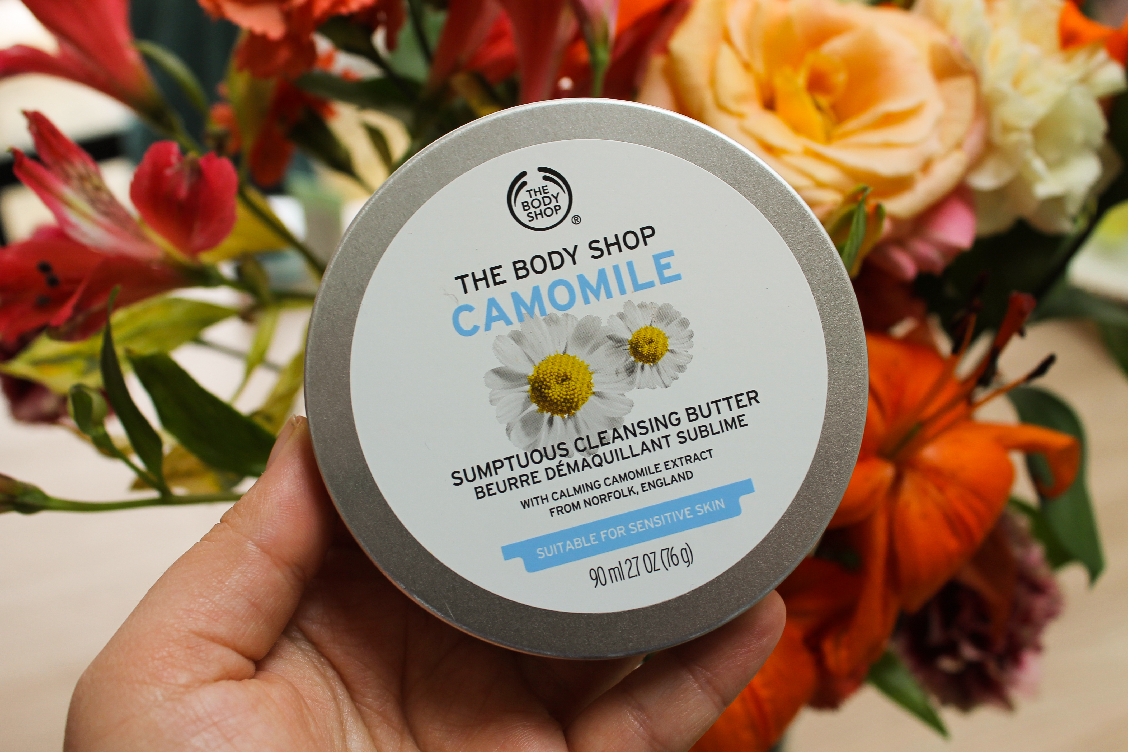 Tin of Camomile Cleansing Butter against a bouquet of flowers