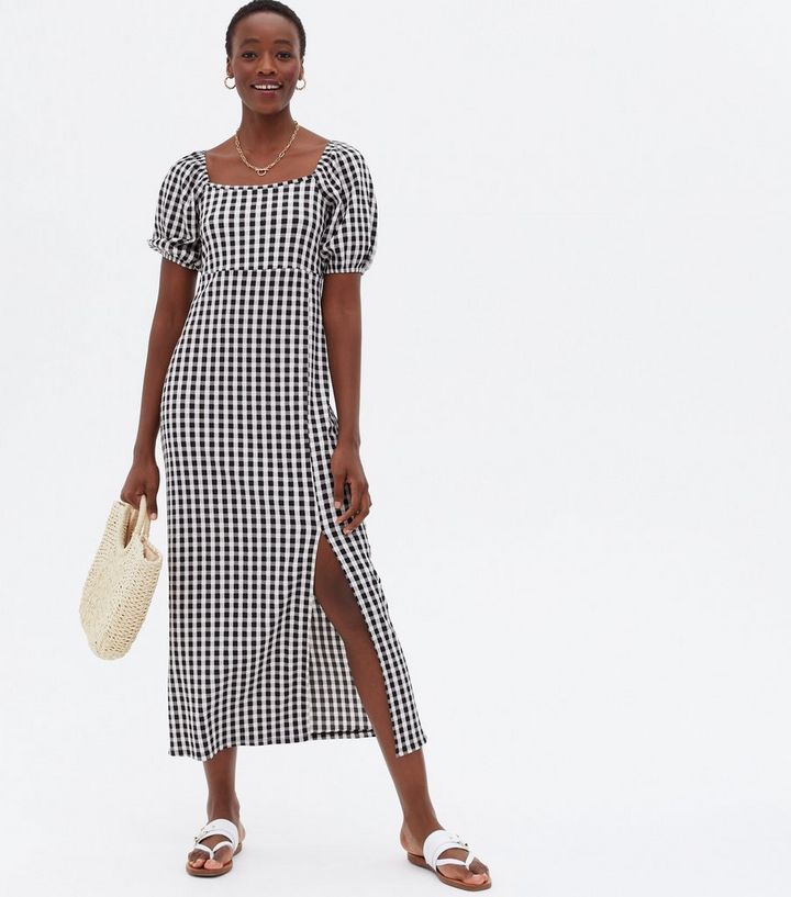 An image of a model wearing a black and white check gingham midi dress with puffy sleeves.